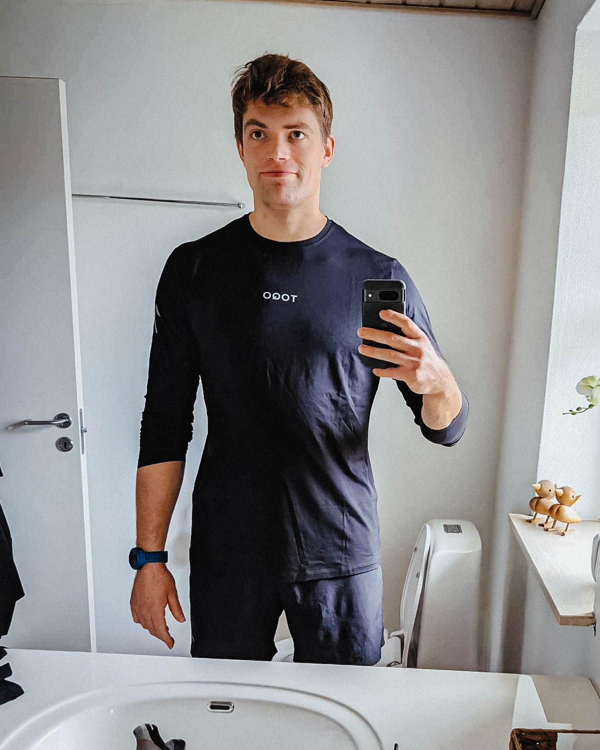 A man standing in the mirror with TOQO clothes